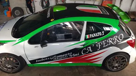 Auto da rally bianca con grafica tricolore verde e nera e sponsor Ca' Ferro