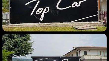 Insegna nera con scritta bianca Top Car su parete esterna, in due inquadrature