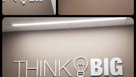 Scritta tridimensionale Think Big con lampadina applicata sulla parete grigia di un ufficio
