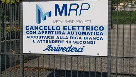 Cartello con logo MRP affisso sul cancello elettrico dell'azienda